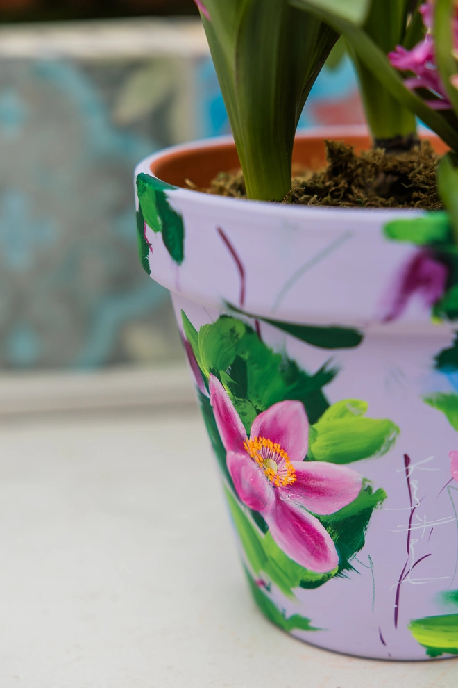 A beautifully hand painted interior terracotta plant pot. Background painted in a pale lilac adorned in pink Japanese anemone. 