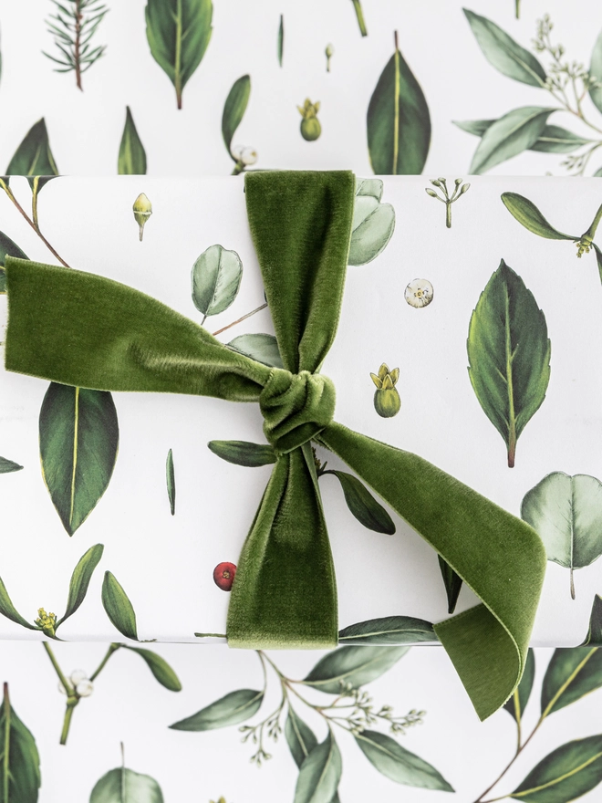 White base Christmas wrapping paper with a green foliage elements pattern