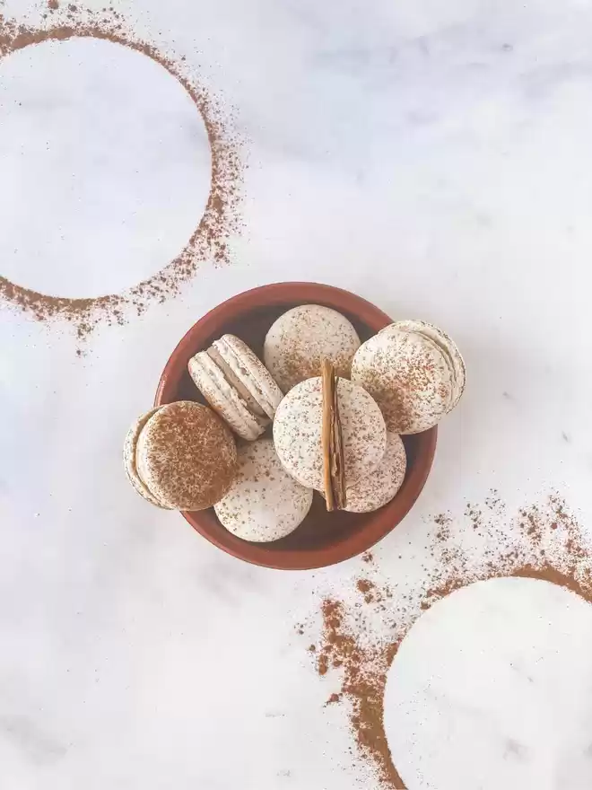 cinnamon sugar macarons in a bowl on a marble surface