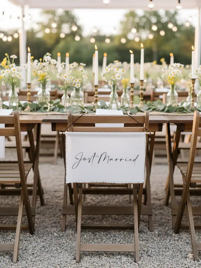 A Just Married linen hanging banner for weddings. Hanging from a rustic top table in a barn. Made from an Italian linen cotton.
