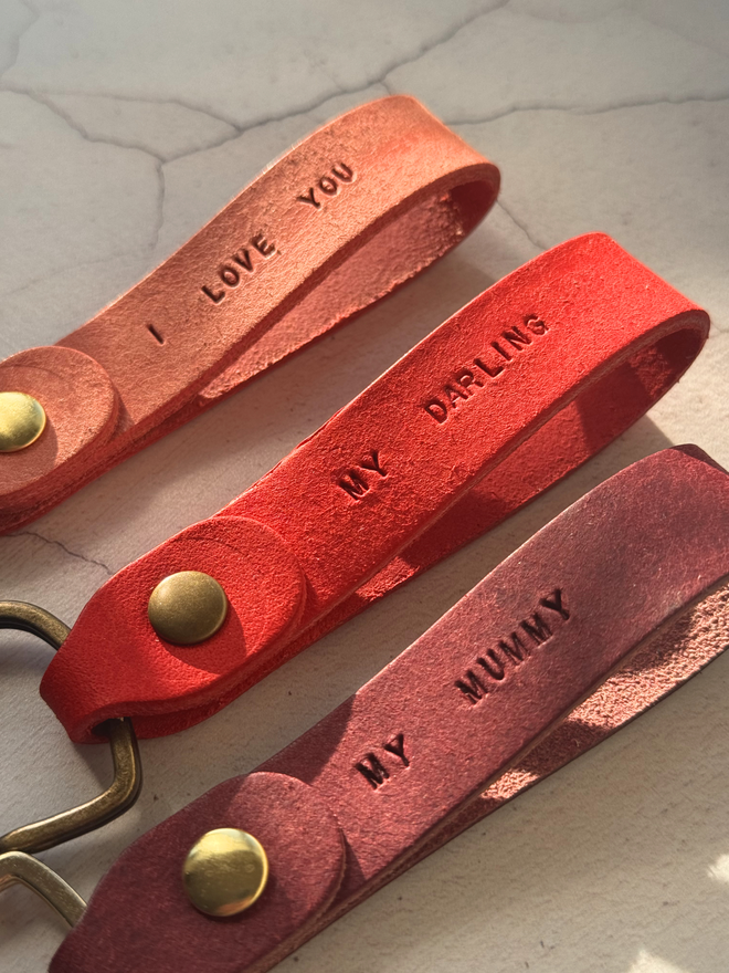 pink leather keyrings stamped with mini text on a white background.