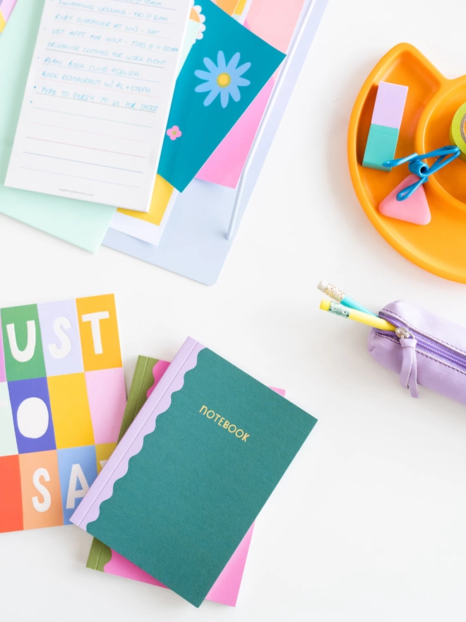 The A6 notebook duo sits on desk with other colourful stationery items from the Raspberry Blossom Happiness Stationery Collection