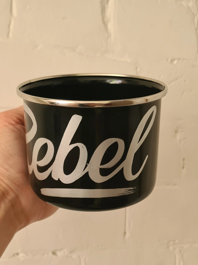 'Rebel' Enamel Mug, a colourful mug sitting on a white surface. held 