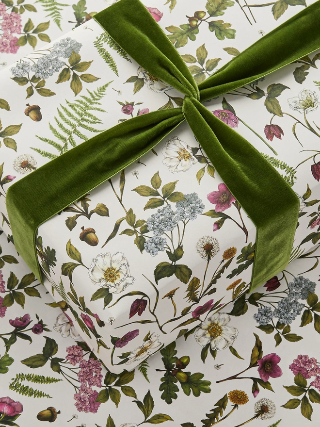 cottage garden floral gift wrap sheet. a box wrapped in multi-coloured illustrated floral gift wrap with a green ribbon.