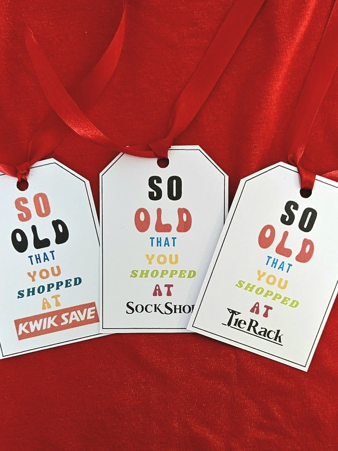 3 tags that say so old that you shopped at Kwik Save Sock Shop Tie Rack in bright colourful letters with a red ribbon