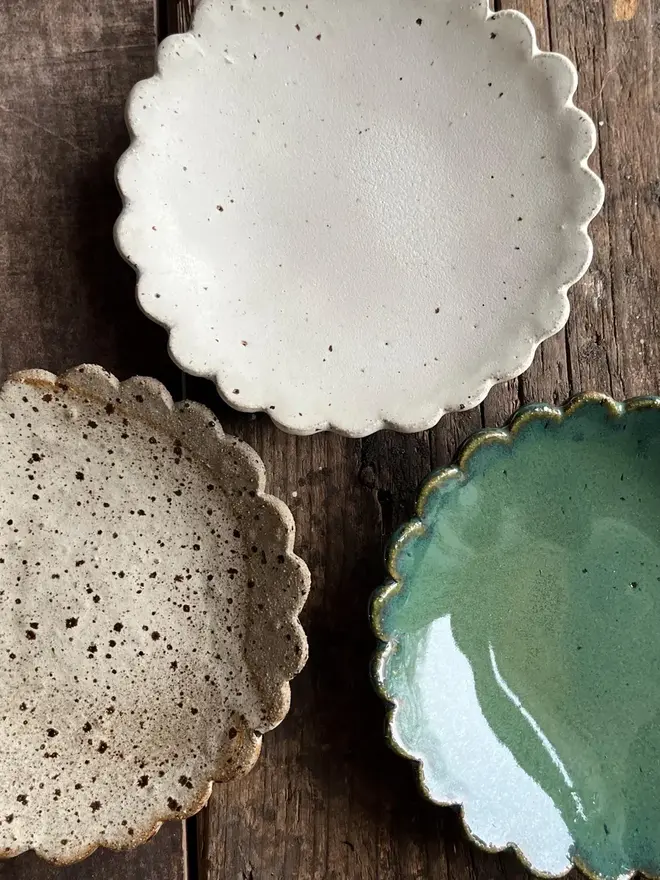 Handmade Scalloped Ceramic Dish, a collection of colourful ceramic plates on a wooden surface.