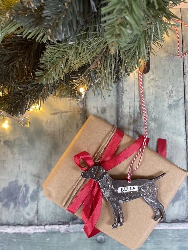 A german shorthaired pointer decoration, hung with red and white twine and placed on giftwrapped gift with a bow