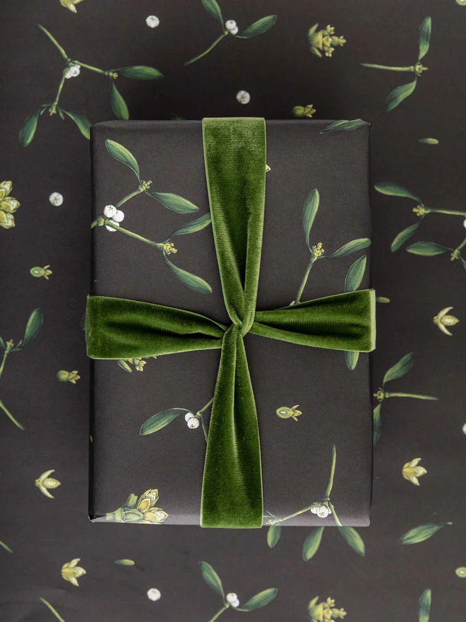 Black based wrapping paper with mistletoe illustration elements