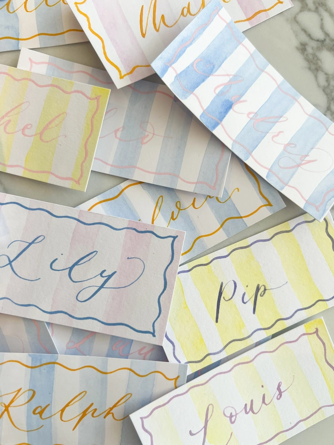 Personalised calligraphy event place cards, striped coloured place cards spread together
