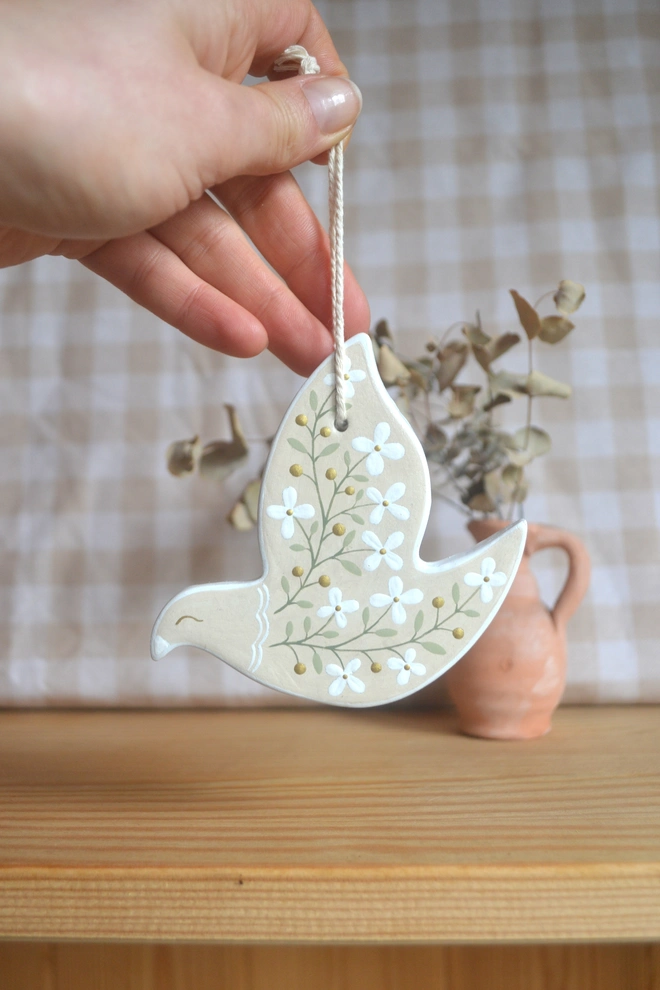 beige ceramic hanging bird ornament with white floral design