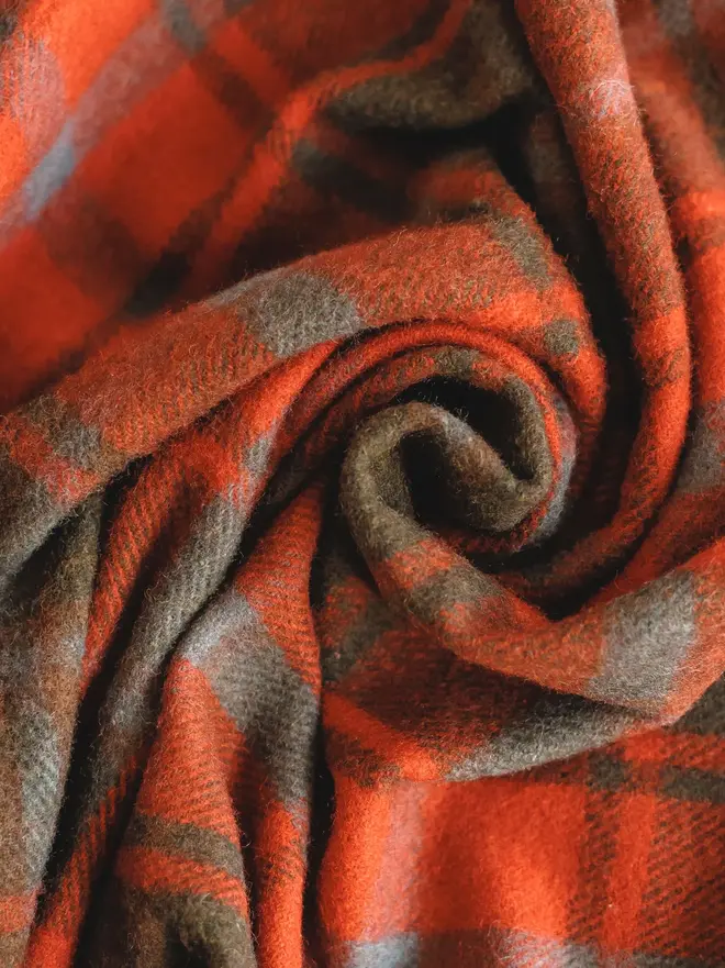 Dark Maple Tartan Blanket, a red blanket curled up. 
