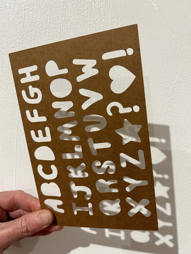 A non plastic stencil with a mini alphabet on it