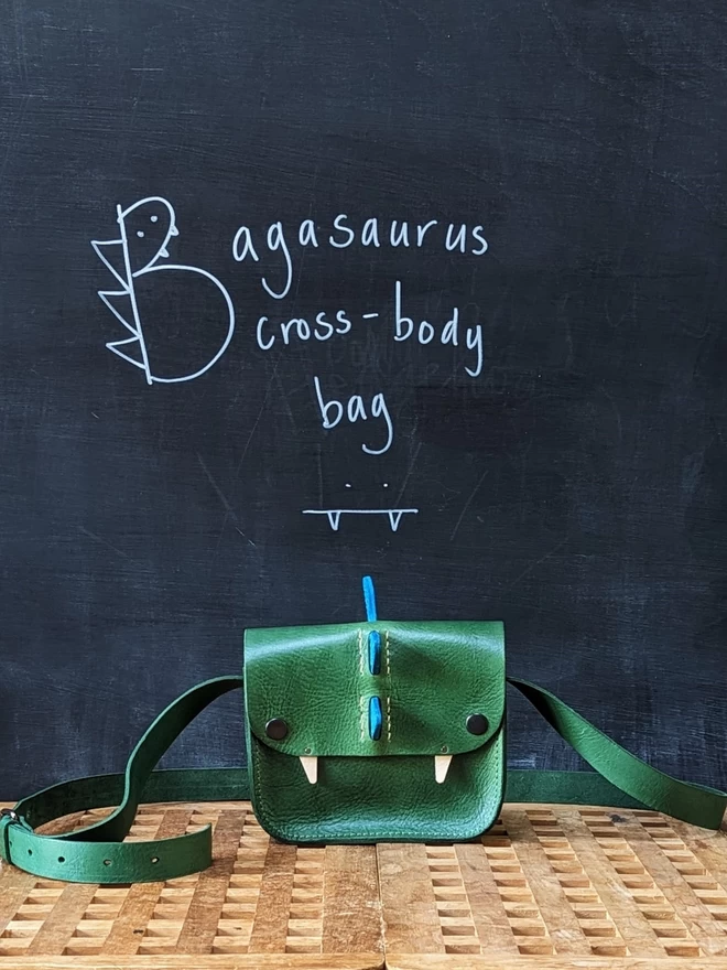  Handmade 'Bagasaurus' cross- body handbag in hand- dyed green leather with forward- facing turquoise spikes.