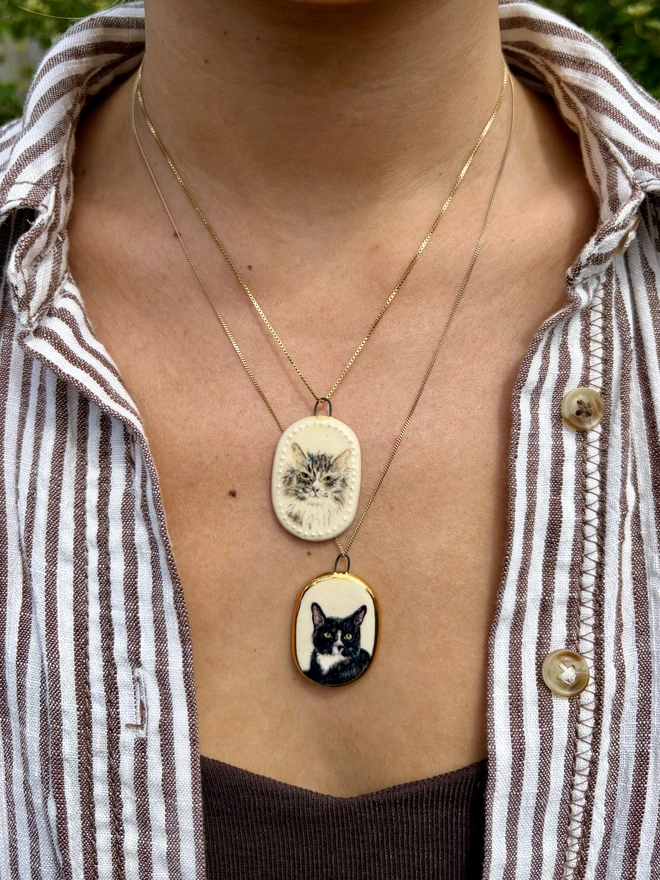 Two miniature pet portrait pendants worn on gold chains as necklaces