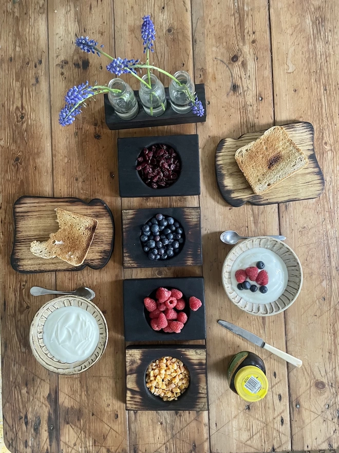 Toast Shaped Oak Serving Board on a Table With Nibble Bowls and Flowers