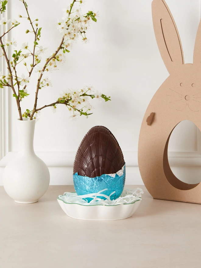 Maple & Pecan Dark Chocolate Easter Egg. a dark chocolate easter egg partially unwrapped from blue foil.
