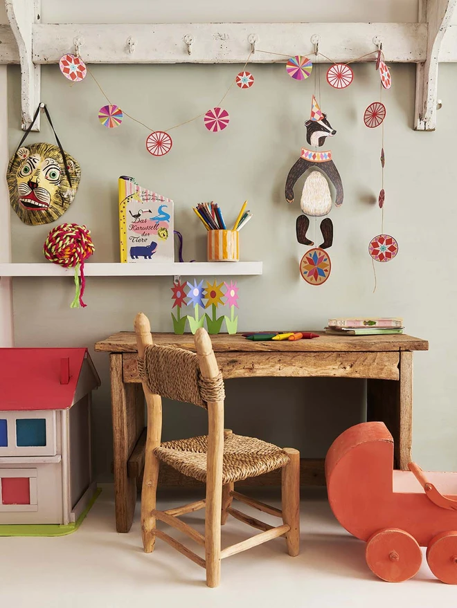 Badger mobile hanging in a kids bedroom near to a dolls house and wooden pram.