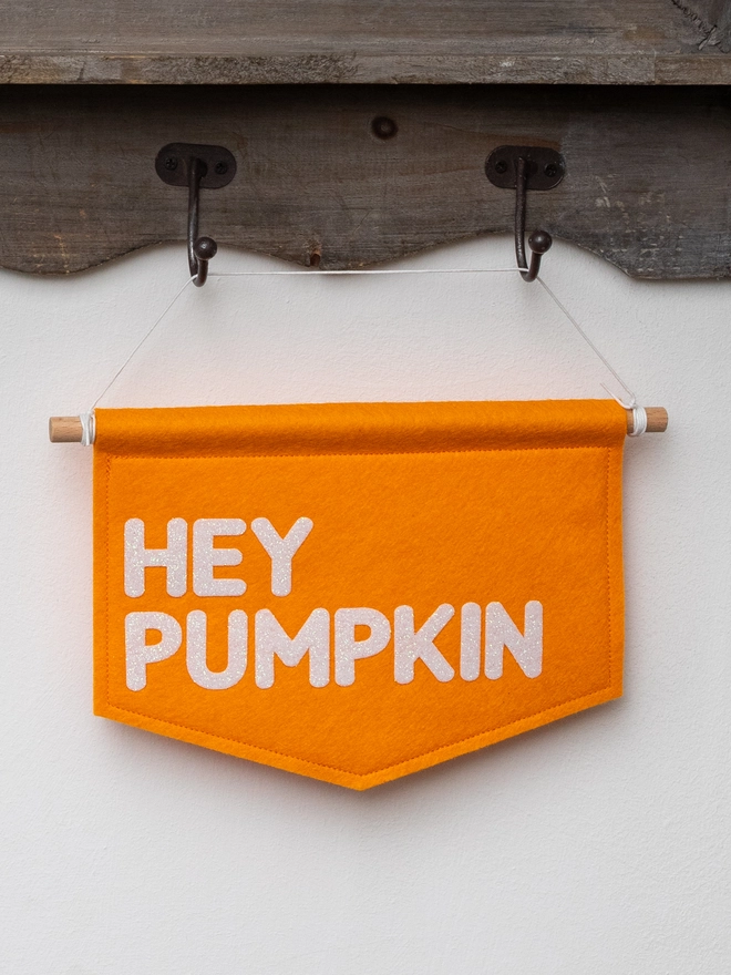 Orange, felt banner with the words "Hey Pumpkin" written on it in white glitter felt