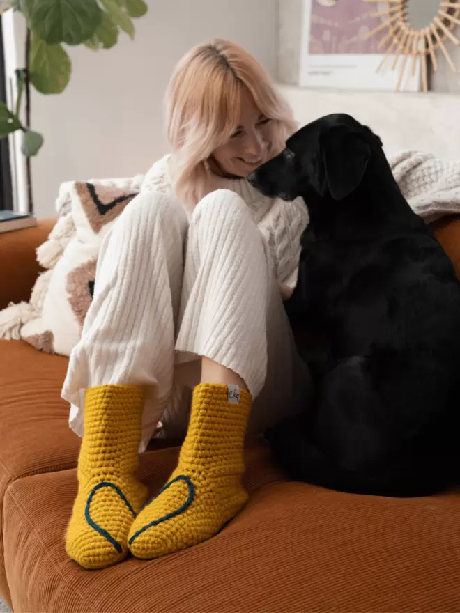 Girl relaxes on sofa with a dog in slipper socks