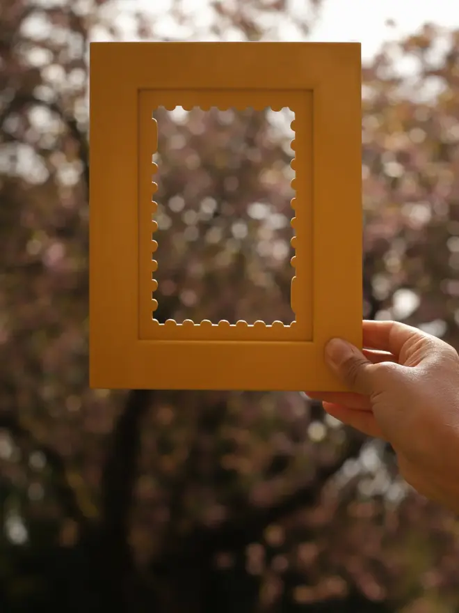 Person holding a yellow frame with matching yellow stamp mount