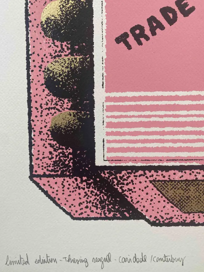 
A close-up photograph of a limited edition A2 screenprint. The print depicts a retro-style matchbox illustration in pink, black, and gold. A large, realistic seagull with a mischievous expression and an open beak is flying across the center. The words "THIEVING SEAGULL" are at the top, and "TRADE MARK" is on either side of the seagull. A banner at the bottom says "MADE IN FOLKESTONE." The background is a solid pink with a slight gold texture. The matches on the side are green and heart-shaped. Below the main image, the print is signed and numbered 3/13. The entire image has a grainy texture, like a vintage screen print.
