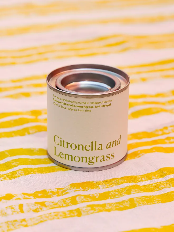 Citronella and Lemongrass Soy Wax Candle Candle, displayed on a yellow and white stripped tablecloth 