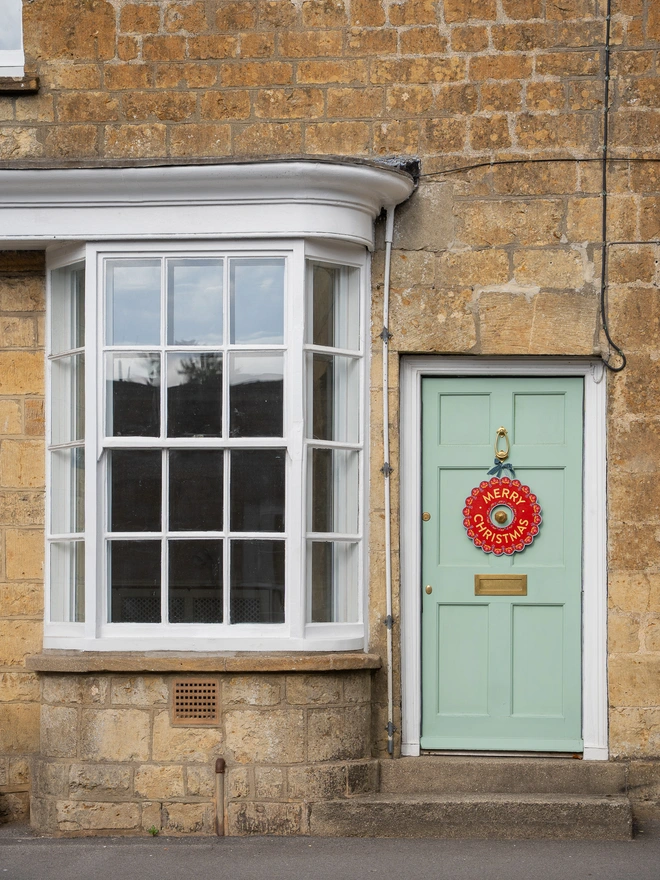 Red Hand painted Christmas Wreath with red lettering and gold leaf lettering on a pale green front door