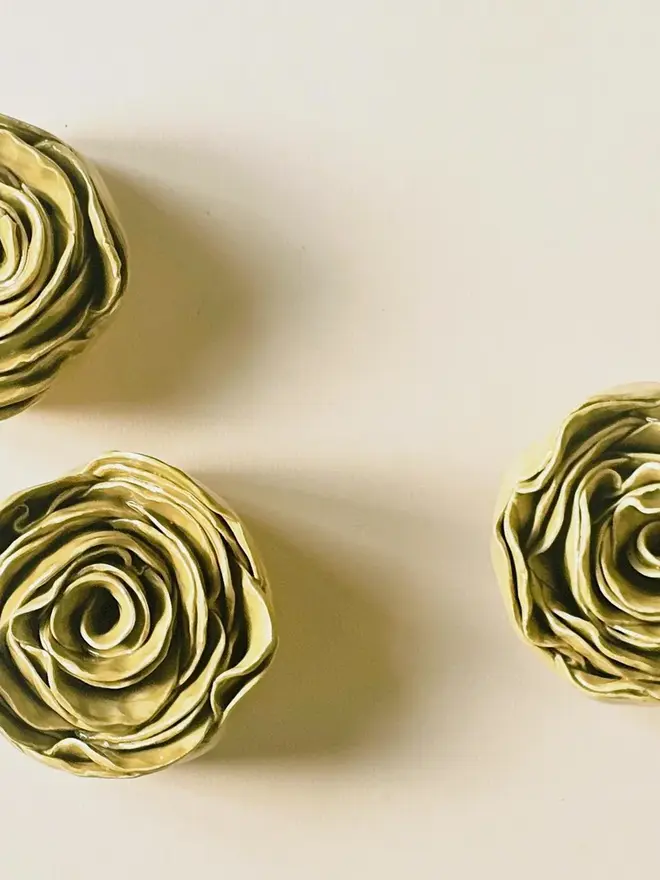 Handmade ceramic rose sculpture with a olive green glossy glaze, crafted in 3D and designed to hang on a wall