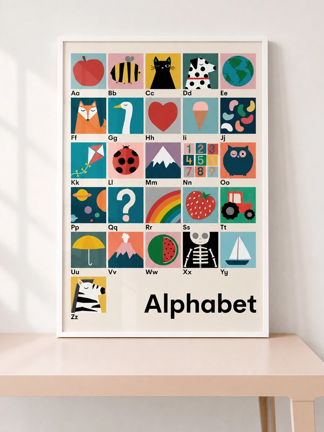 A childrens  A-Z alphabet poster featuring vibrant illustrations of various objects, such as an apple, cat, and rainbow. The word "Alphabet" is printed below the illustrations.