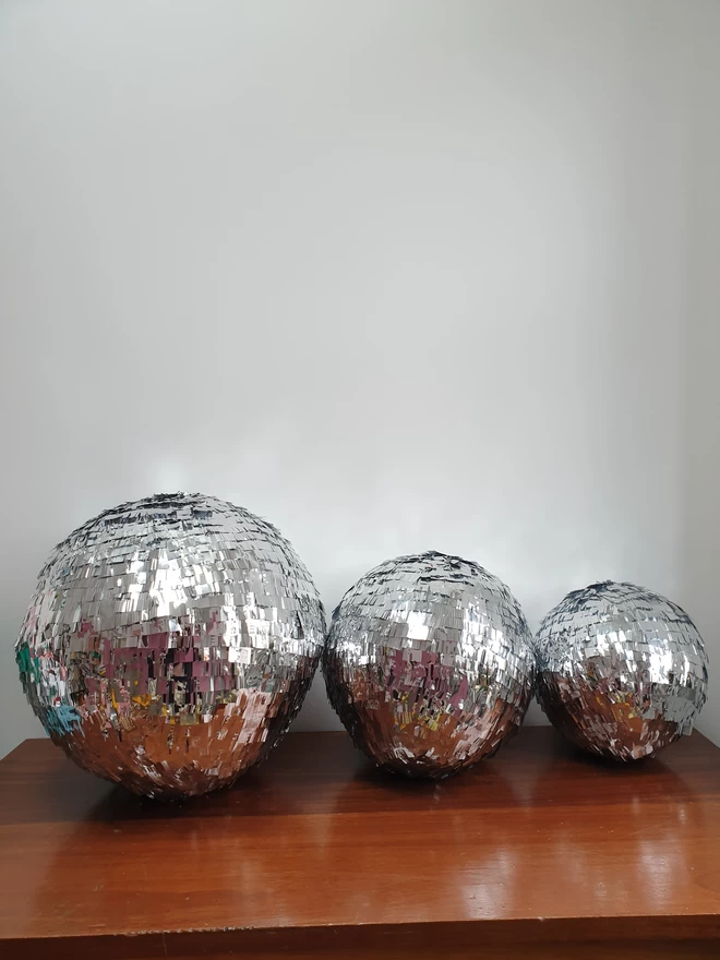 Small medium and large disco ball pinatas lined up next to each other