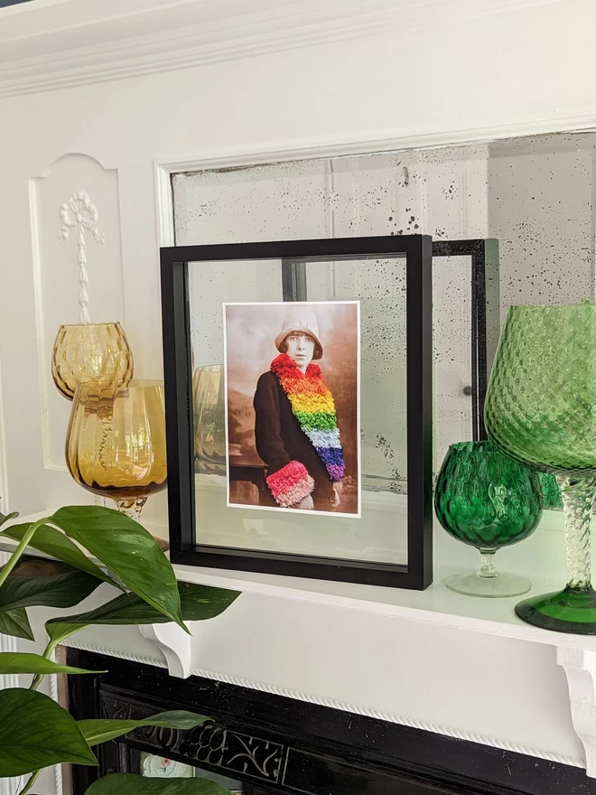  Print of woman wearing embroidered rainbow coloured trim coat framed on mantlepiece