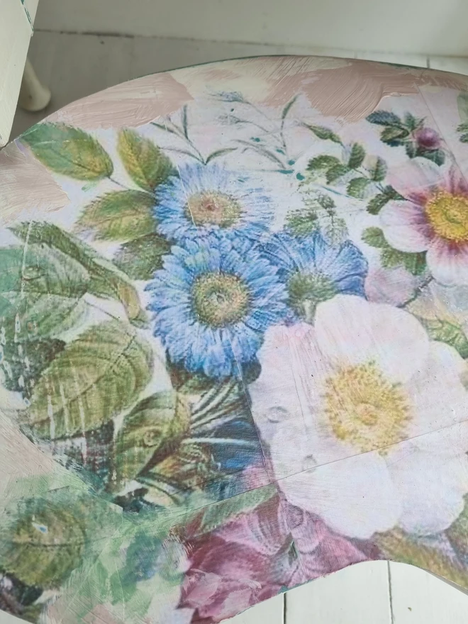A painted dressing table in white and pale pink with large florals in blues and mauves and text in turquoise that reads 'turn your face to the sun'. The whole piece is distressed in the shabby chic style.