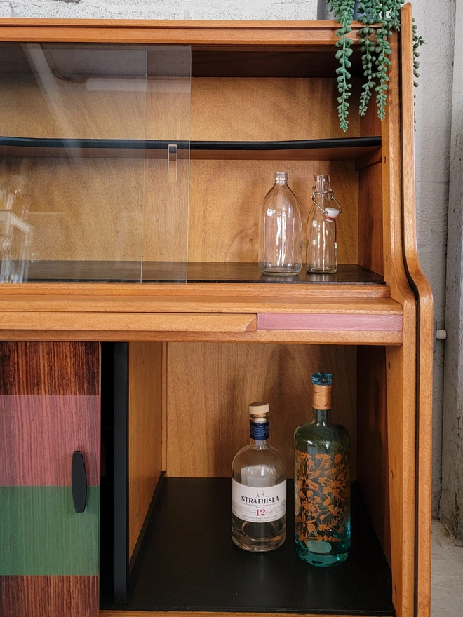 Teak sideabord storage shelves with bottles and a plant