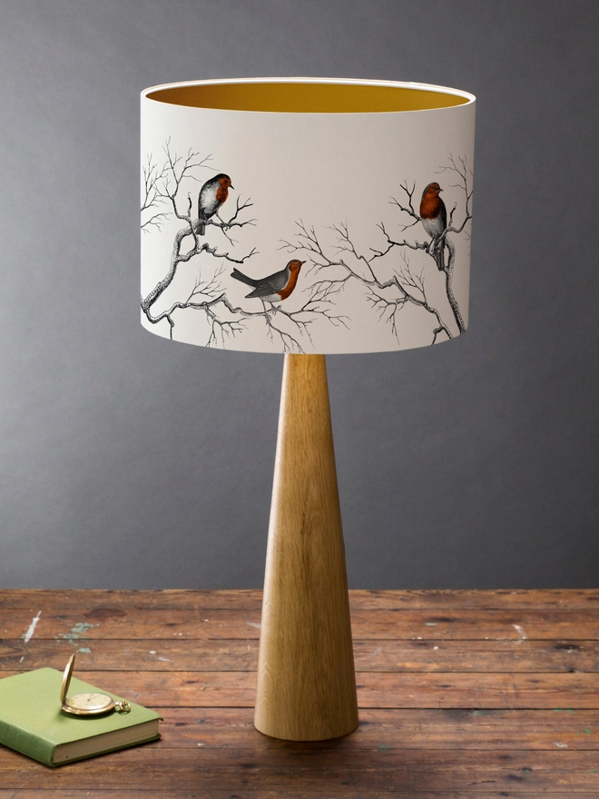 Drum Lampshade featuring Robins on a wooden base on a shelf with books and ornaments