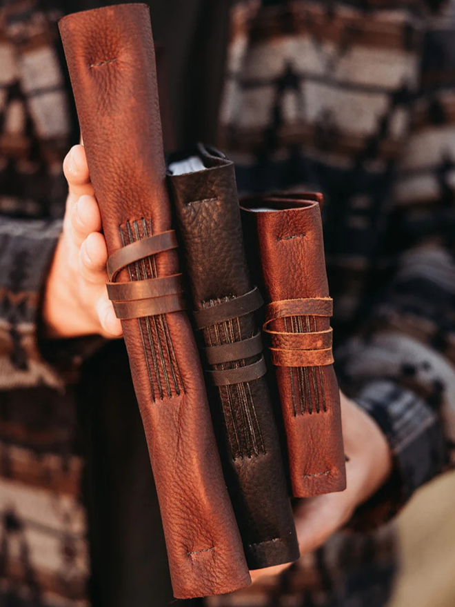 reclaimed saddlery leather journal. a stack of three different sized brown leather  journals.