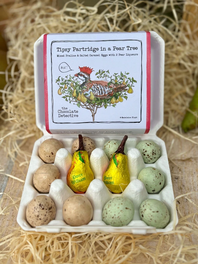 A box of wonderful Partridge in a pear tree chocolate eggs on a table surround by wood wool