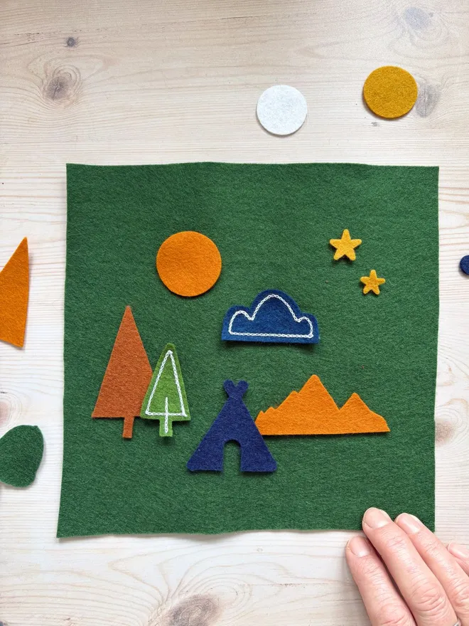 A piece of felt with cut out shapes on top on a wooden background