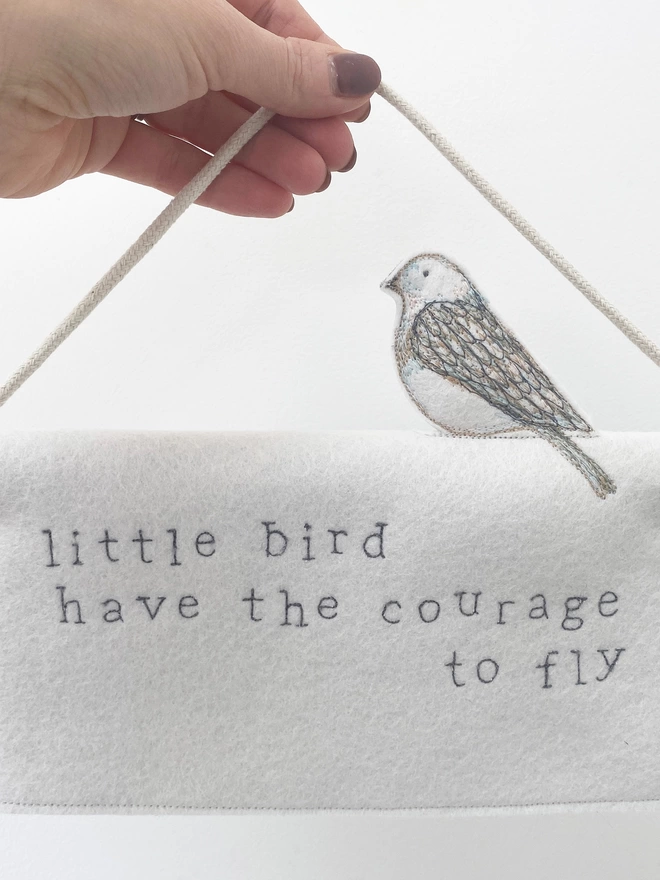little bird have the courage to fly felt banner held in hand