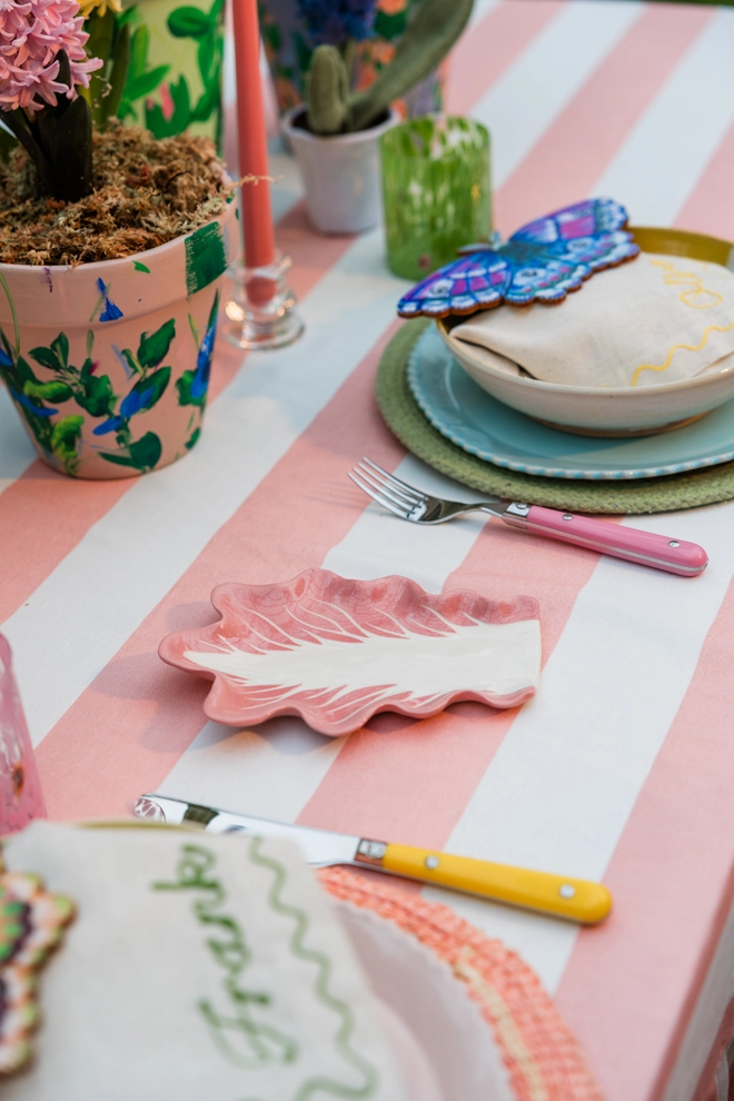 Radicchio Leaf Spoon Rest in Radicchio Pink as part of a larger tablescape with a pink and white tablecloth, painted plant pots and colourful cutlery