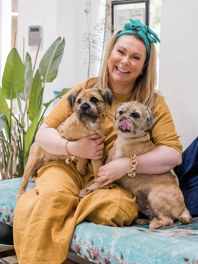 A picture of Holly Tucker, founder of Holly & Co, with seated with her Border Terrier Dogs, Mudley and Chewy