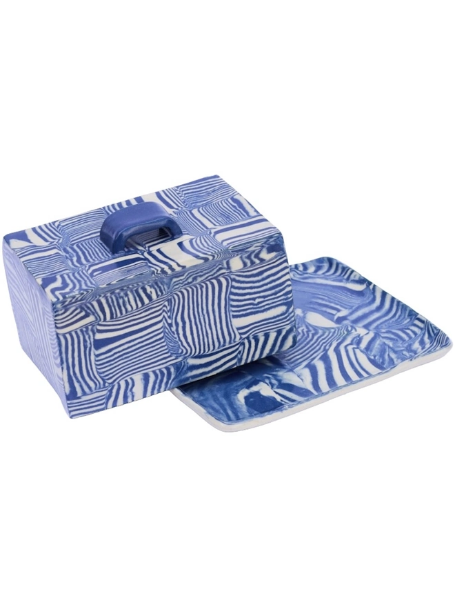 Striped Butter Dish, a colourful striped butter dish sitting on a white surface against a plain backdrop. 