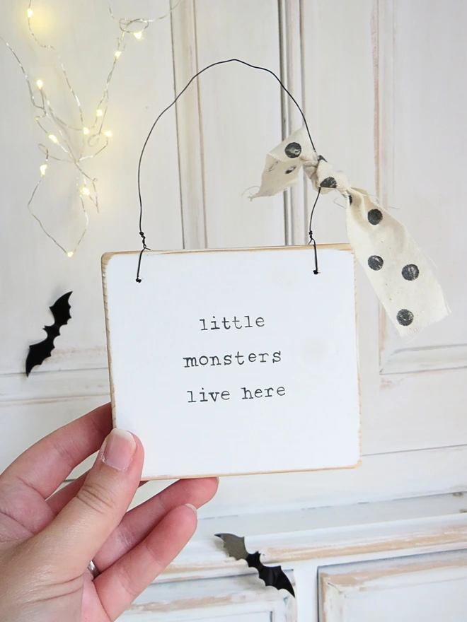 hand painted white wooden sign with hand painted little monsters message