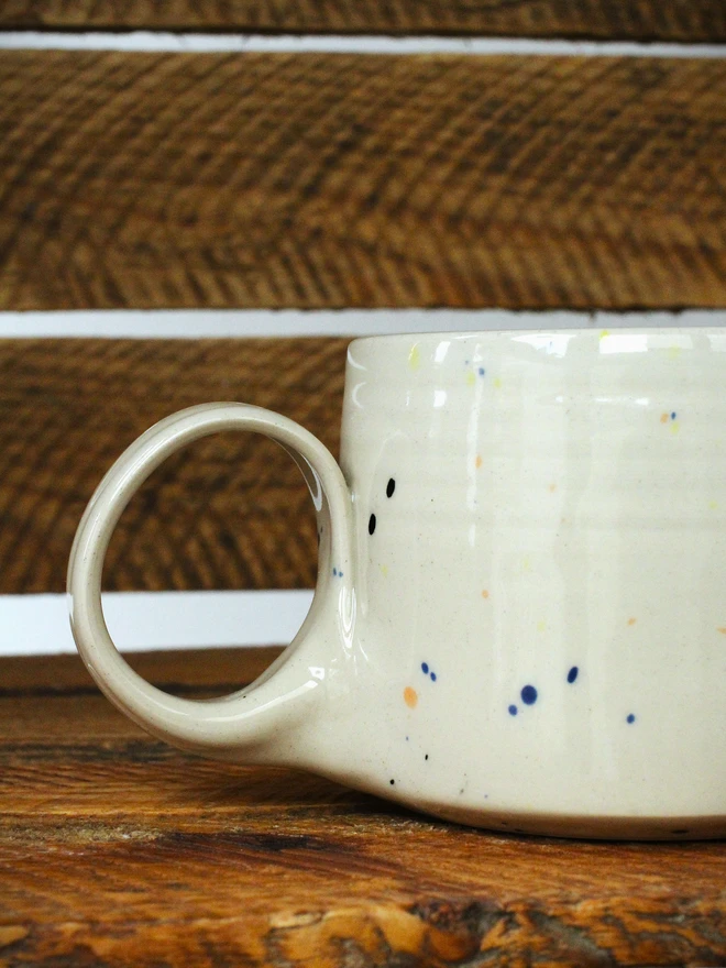Small creamy white terrazzo cups with black, blue, and yellow splatters and glossy glaze