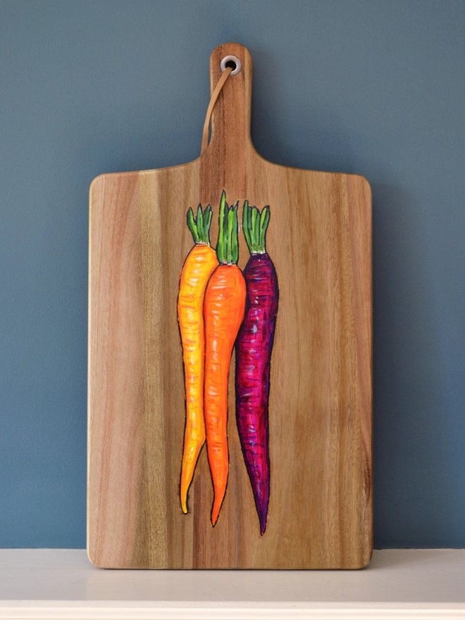 Wooden serving board with a handpainted carrots design