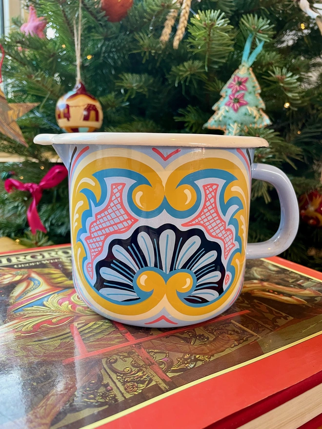 Blue enamel jug hand painted with a fairground design in blue, pink and yellow