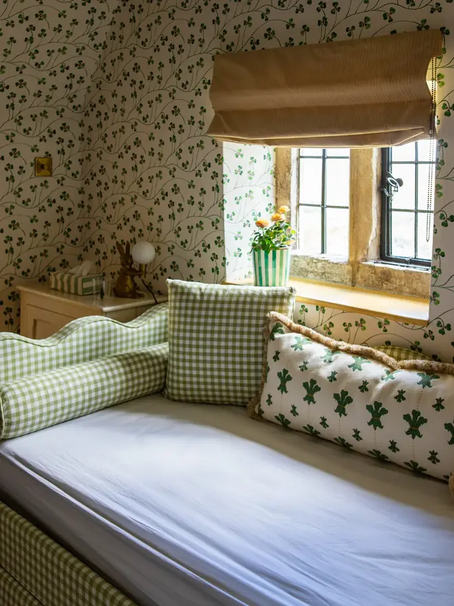 'the lochlan' green gingham upholstered children's bed. a green gingham sofa-style with a wavy headboard, photographed in a bedroom in front of a window.