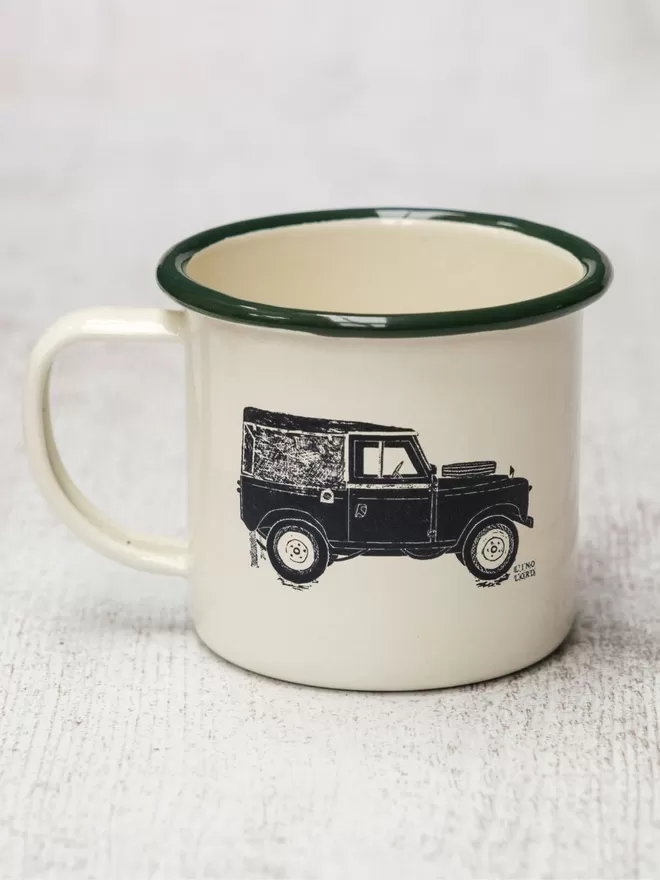 Picture of a Cream Enamel Mug with a Green Rim with a Land Rover design etched onto it, taken from an original Lino Print