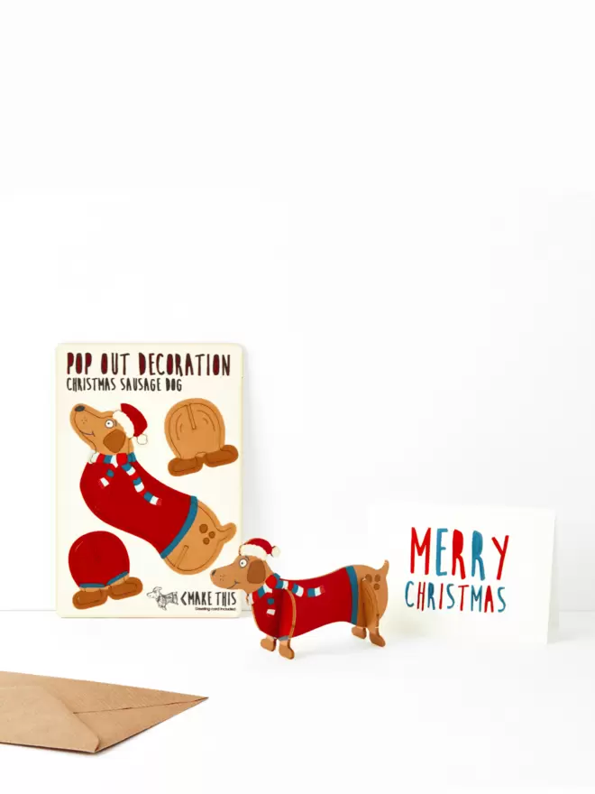 Sausage Dog Christmas decoration and Merry Christmas card and brown kraft envelope on a white background