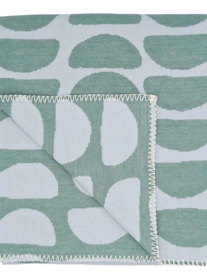 Organic Cotton Throw, a cotton throw folded into a square on a floor. 