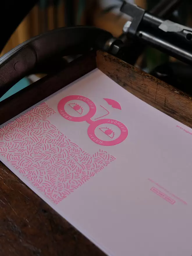 Pink 'Big Hair, Big Style' card on printing press.